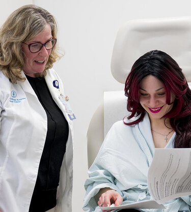 Doctor and patient review documents, smiling in a clinical setting.
